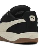 Championes Puma modelo Park Luna SD, de estilo urbano con capellada de gamuza negra y detalles en color arena. Presenta la icónica franja lateral de la marca en contraste, entresuela de goma y suela de caucho color caramelo.