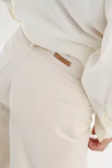 Pantalón color crudo, de corte recto, con bolsillos frontales y traseros, costuras contrastantes y cierre frontal.