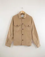 Camisa de pana color beige, de manga larga, con cuello camisero, cierre frontal de botones y dos bolsillos de parche con solapa en el pecho. Presenta un corte recto y holgado.