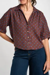 Blusa de lino y viscosa color marrón con estampado de lunares azules, cuello camisero, cierre frontal con botones y mangas cortas.