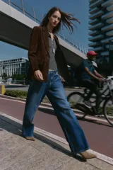 Blazer de piel 100% color marrón oscuro, con cuello solapa, manga larga con hombreras y bolsillos delanteros con solapa. Presenta pespuntes decorativos en contraste y cierre frontal con un botón.