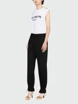 Remera blanca sin mangas de algodón con el logo de Balmain estampado en negro en el pecho y botones dorados en el hombro.