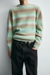 Jersey de punto con ajuste relajado, cuello redondo y manga larga. Presenta un diseño de rayas horizontales difuminadas en tonos verde agua y marrón, con acabados en rib en cuello, puños y ruedo.