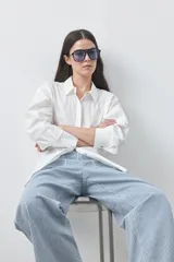 Camisa de manga larga de algodón en color blanco, con cuello clásico, cierre frontal de botones y silueta relajada.