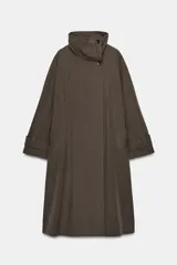 Trench oversize de Zara Woman Collection, confeccionado en mezcla de algodón con estampado de cuadros pequeños. Presenta cuello alto, cierre frontal con botones, mangas largas con trabillas ajustables y bolsillos laterales.