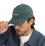 Gorra de visera curva color verde, con el logo de la marca 'Rhythm.' bordado en blanco en el frente.
