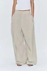 Pantalón de tiro medio color marrón, con pinzas en el delantero, perneras anchas de corte recto y trabillas para cinturón. Cuenta con bolsillos laterales y traseros, y cierre frontal con cremallera y botón.