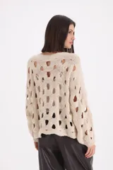 Sweater de punto color beige con diseño de calados circulares en toda la prenda, cuello redondo y mangas largas con puños acanalados.