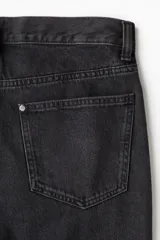 Jeans de cinco bolsillos en denim de algodón rígido, color negro lavado. Modelo de cintura estándar con cierre y corte relajado de cadera a bajo con pierna recta amplia.