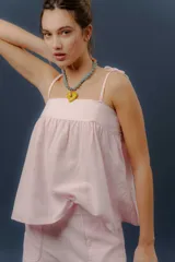 Conjunto de dos piezas confeccionado en lino color rosado, compuesto por una musculosa de corte amplio con breteles de lazo regulables y un short con elástico en la cintura y bolsillos delanteros redondeados.