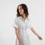 Vestido camisero blanco con botones dorados, corte a la cintura y mangas cortas con dobladillo.