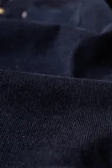 Camisa de manga larga confeccionada en pana gruesa de color azul marino. Presenta cuello con botones, cierre frontal con botones en contraste y un bolsillo en el pecho con etiqueta de marca.