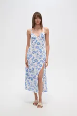 Vestido largo de viscosa, estampado en tonos blanco y azul con diseño floral tipo cachemir. Presenta escote en V, tirantes finos, talle ajustado con cordón y abertura lateral en la falda.