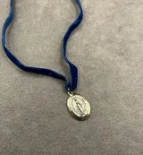 Collar con cinta de terciopelo azul y medalla milagrosa de metal plateado.