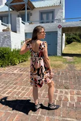 Vestido corto con estampado abstracto en tonos rosa, beige, negro y rojo. Tiene escote cuadrado, breteles anchos con volados y corte holgado.