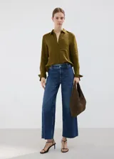 Jeans de denim azul de corte wide leg, tiro medio y diseño clásico con bolsillos y cierre frontal.