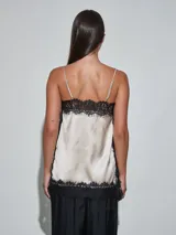 Musculosa de satén color beige claro, con detalles de encaje negro en el escote, los laterales y el ruedo, y tirantes finos.