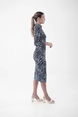 Vestido midi de corte ajustado, con estampado animal print tipo cebra en blanco y negro, cuello camisero, escote en V y cierre frontal con botones dorados.
