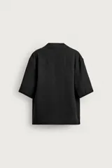Camisa tipo kimono de corte relaxed fit, color celeste, confeccionada en tejido fluido de viscosa y lino. Presenta cuello con solapas de muesca, manga corta y cierre frontal cruzado con doble botonadura.