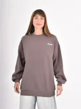 Buzo de cuello redondo en color gris oscuro, con corte holgado y mangas largas con puños elásticos. Presenta un pequeño bordado en el pecho con la palabra 'Cupid' y un corazón.