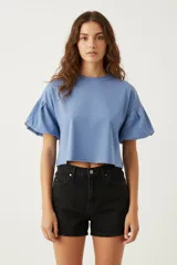 Remera de algodón color azul, con cuello redondo a la base y mangas cortas abullonadas con elástico.