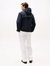 Campera azul marino con capucha, cierre de cremallera, dos bolsillos en la cintura y puños elásticos con botones a presión. Tiene un parche con el logo de Tommy Hilfiger en la manga.