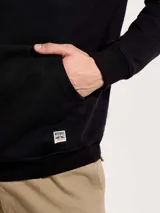 Buzo con capucha de corte clásico, color negro, con bolsillo frontal tipo canguro y puños acanalados.