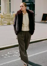 Chaqueta de pelo sintético en color marrón oscuro, con diseño recto, cuello solapa, cierre frontal con cremallera y manga larga.