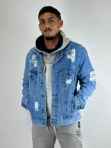 Campera de jean celeste con roturas y desgaste, de corte clásico, con cuello camisero, cierre frontal con botones metálicos, bolsillos con solapa abotonada en el pecho y bolsillos laterales.