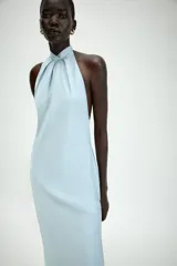 Vestido midi de satén color celeste, con cuello halter y detalle de lazada en la espalda descubierta.