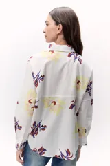 Camisa blanca con estampado floral en tonos amarillo, rojo y azul, de corte recto y manga larga.