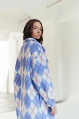 Camisa larga con estampado de rombos en tonos celeste, blanco y rosa. Tiene cuello camisero, cierre con botones y bolsillos frontales.