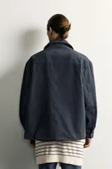 Sobrecamisa regular fit confeccionada en tejido de algodón negro con estructura canvas. Tiene cuello solapa, manga larga con puño abotonado, bolsillos de plastrón con solapa en la cadera y un bolsillo en el pecho. Cierre frontal con botones ocultos bajo solapa.