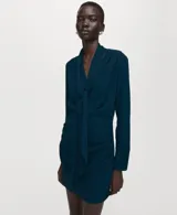 Vestido corto azul oscuro, de manga larga y escote en V, con detalle de bufanda integrada al cuello y fruncidos laterales en la falda.