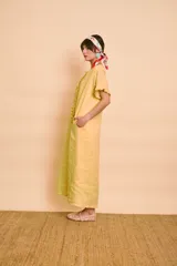 Vestido tipo túnica largo de lino color amarillo, de manga corta, con bolsillos laterales y detalle de volados en la botonera frontal.