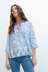 Camisa de mangas 3/4 con estampado abstracto en tonos azules y blancos, con cuello clásico y cierre frontal con botones.
