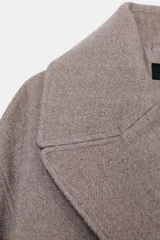 Abrigo corto de paño en color marrón chocolate, con cuello de solapa, cierre frontal cruzado con botones y mangas largas con detalle de trabilla y botón en los puños.