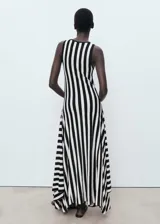 Vestido largo de punto fino con diseño evasé, cuello caja y tirantes anchos. Presenta un estampado de rayas verticales en blanco y negro y un bajo asimétrico.