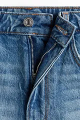 Short de denim de tiro superalto y corte clásico con cinco bolsillos, confeccionado en algodón rígido. Presenta detalles de roturas y efecto desgastado en la parte frontal, además de bajos deshilachados con flecos.