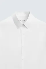 Camisa negra de corte slim fit, con cuello italiano y manga larga con puño abotonado. Cierre frontal de botonadura.