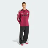 Suéter de punto Adidas en color bordó, inspirado en el estilo de las camisetas de fútbol retro. Presenta cuello redondo, mangas largas con las tres tiras características de la marca en blanco y detalles perforados en la trama. Incluye el logo del Trifolio y un escudo circular bordados en el pecho, junto con el texto "adidas" en contraste.