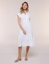 Vestido midi blanco estilo camisero de la marca Julia Jordan, confeccionado en tejido broderie 100% algodón. Presenta cuello camisero tradicional, cierre frontal con botones, mangas cortas con vuelta y cintura entallada con pinzas que da paso a una falda evasé. Cuenta con forro interior.