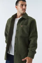 Sobrecamisa color crema de poliéster con textura de sherpa, cuello camisero, cierre con botones marrones, bolsillo de parche en el pecho y logo en etiqueta de cuero. Corte recto.