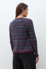 Chaqueta de tejido de punto con textura, diseño multicolor en tonos azul, rojo y blanco. Presenta cuello redondo, cierre frontal y detalles de flecos en los bordes y puños.