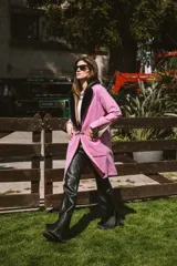 Pantalón de cuero de tiro alto con corte oxford, presenta un tajo en el ruedo lateral y un botón metálico distintivo.