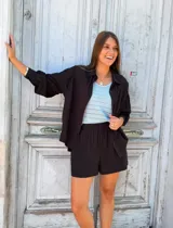 Conjunto de dos piezas color negro compuesto por una camisa de manga larga con botones frontales y un short de tiro alto con cintura elástica.