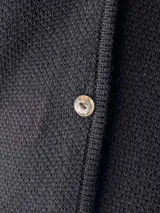 Chaleco negro de punto con cuello en V y cierre frontal con botones.