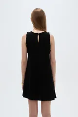 Vestido corto sin mangas en tono beige natural, con cuello redondo y volados delicados en las sisas.