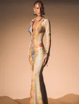 Vestido largo de silueta ajustada con estampado de piel de serpiente en tonos cálidos. Presenta escote profundo con cuello tipo camisa, mangas largas y recortes laterales cut-out que estilizan la figura.