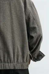 Sobrecamisa de corte cropped confeccionada en tejido ligero con algodón, con estampado de cuadros pequeños en tonos oscuros. Presenta cuello solapa, cierre frontal de botones, manga larga con puño abotonado y bajo con elástico en la espalda.